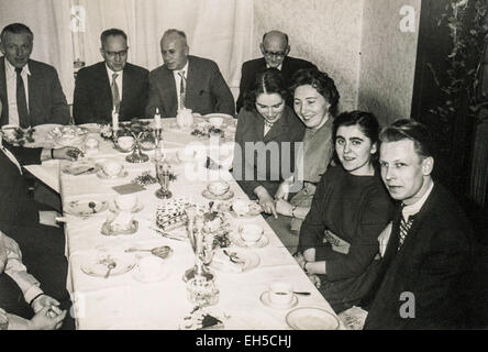 L'Allemagne. 28 Février, 2015. CIRCA 1960 : un groupe d'hommes et de femmes assis à une table sur laquelle se trouve le gâteau et verres © Igor Golovniov/ZUMA/Alamy Fil Live News Banque D'Images