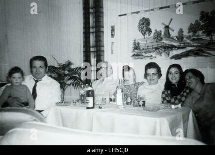 L'Allemagne. 28 Février, 2015. CIRCA 1950 : Groupe de gens assis à la table du banquet. Sur la peinture du mur accroché avec le paysage traditionnel avec moulin © Igor Golovniov/ZUMA/Alamy Fil Live News Banque D'Images