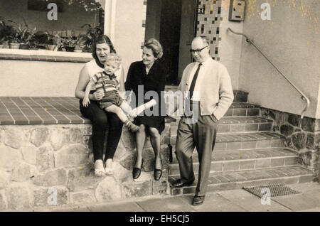 L'Allemagne. 28 Février, 2015. CIRCA 1960 : Jeune femme avec un petit garçon dans un T-shirt rayé et short en main posant avec ses parents près d'une maison privée © Igor Golovniov/ZUMA/Alamy Fil Live News Banque D'Images