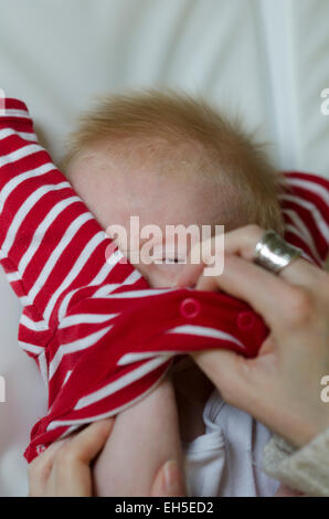 A 10 semaines bébé garçon triste et irrité à être habillé. Banque D'Images