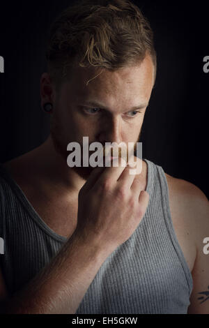 Jeune homme de pensée / rocker avec tatouages et d'oreille. Banque D'Images