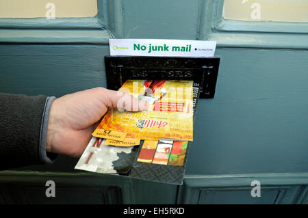 Mans part en poussant le courrier indésirable par letterbox sans signe au-dessus de courrier indésirable, Département du Nord-Ouest de l'Angleterre, Royaume-Uni Banque D'Images