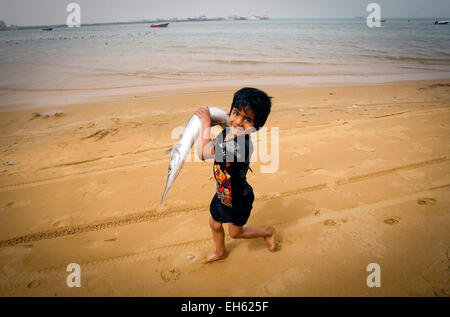 Téhéran, Iran. 7 mars, 2015. Un garçon d'une famille de pêcheurs porte un poisson sur la plage, dans la ville portuaire de Chabahar, dans le sud-est de l'Iran, le 7 mars 2015. © Ahmad Halabisaz/Xinhua/Alamy Live News Banque D'Images