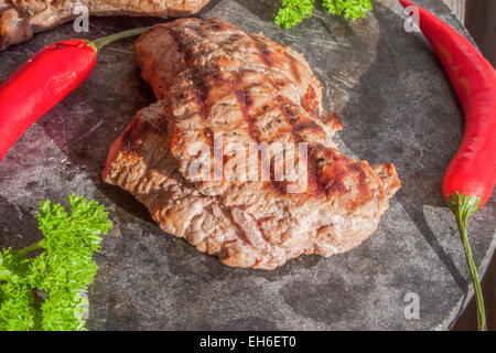 La viande d'Orignal, près de piments et le persil. Sur une plaque en pierre Banque D'Images