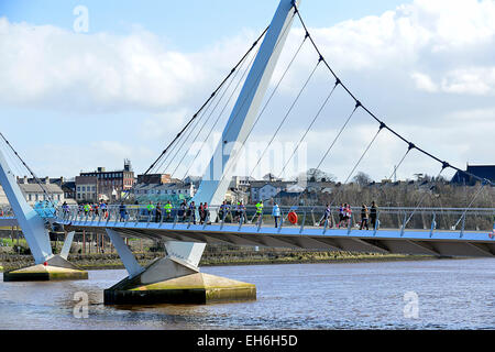 Londonderry, en Irlande du Nord, Royaume-Uni. 8 mars, 2015. Météo France : Sunshine et douches à Londonderry, en Irlande du Nord - 08 mars 2015. Concurrents de la SSE 10k d'Airtricity demi-marathon cross Londonderry's iconic Peace Bridge. Les prévisions pour l'Irlande du Nord aujourd'hui est d'éclaircies et averses éparses avec marche rapide d'ouest dominants. Crédit : George Sweeney/Alamy Live News Banque D'Images