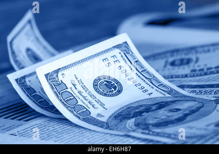 Image teintée de bleu selective focus shot. Cent billets d'un dollar sur les pages financières des journaux grand format Banque D'Images