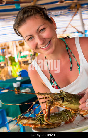 Girl holding un homard cru et souriant Banque D'Images