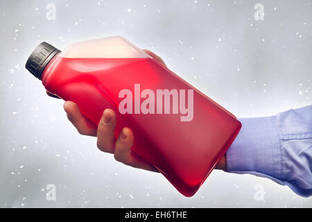 Homme main tenant une bouteille d'additif antigel liquide à base d'eau pour l'hiver l'état de conduire. La tonalité de l'image. Banque D'Images