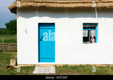 Mur Blanc du pays maison paysanne avec une porte bleue et une fenêtre. Rag-doll, cache-pot et une bobine de corde dans le bas de caisse Banque D'Images