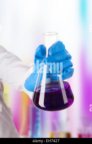 Hand holding liquide chimique en laboratoire dans un flacon de verre Banque D'Images