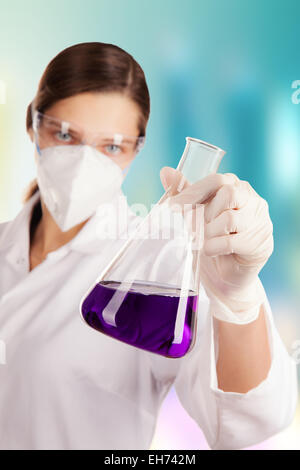 Femme en tenue de laboratoire produit chimique liquide dans un flacon de verre Banque D'Images