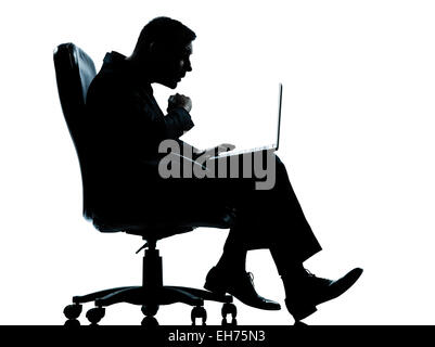 Un homme d'affaires caucasiennes informatique ordinateur surpris assis dans un fauteuil en pleine longueur silhouette studio isolé sur fond blanc Banque D'Images