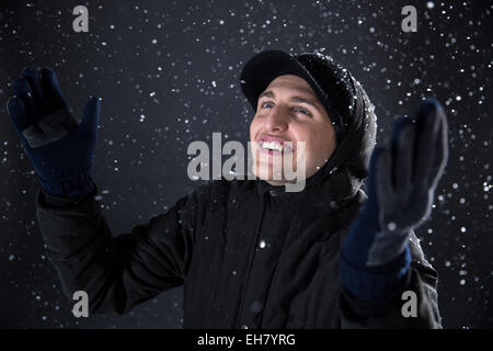 Heureux homme jouit de la neige en fond noir Banque D'Images