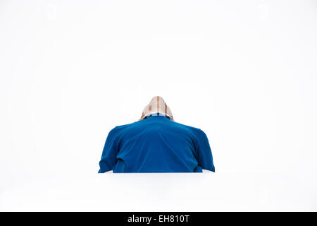 L'homme assis à la table et à la recherche sur fond blanc Banque D'Images