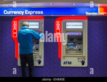 À l'aide de l'homme bureau de change Travelex DISTRIBUTEUR AUTOMATIQUE à l'aéroport de Manchester. L'Angleterre. UK Banque D'Images