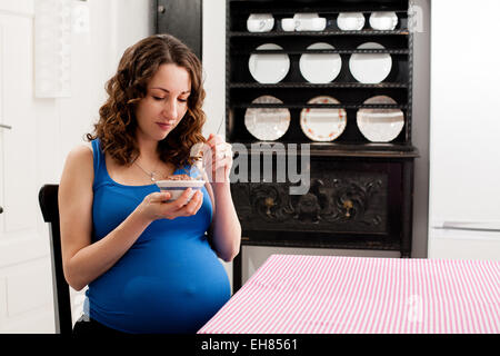 Femme en grossesse à terme plein de manger du chocolat au lait. Banque D'Images