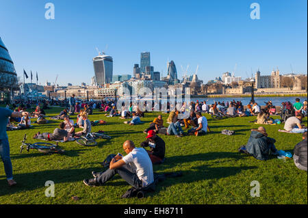 Des gens assis sur l'herbe à Tower bridge Londres. Banque D'Images