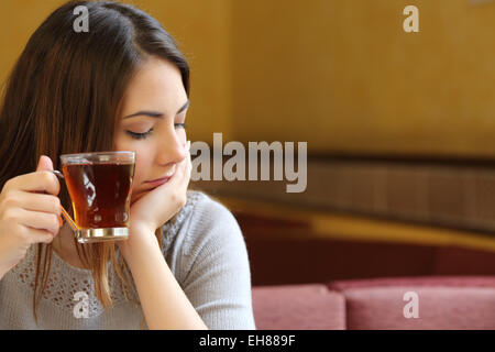 Jeune femme assise détendue dans un café avec une tasse de thé et de la pensée Banque D'Images