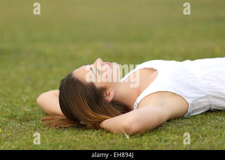 Relaxed woman lying on the grass dormir dans une scène paisible avec un fond vert Banque D'Images