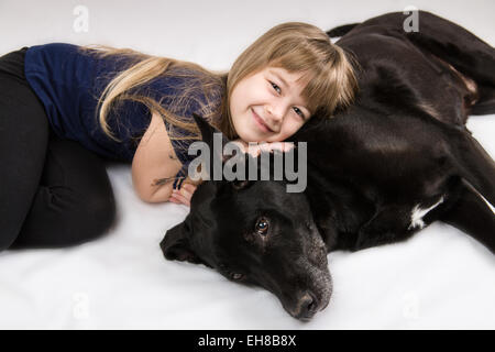 Sept ans, fille, posant sa tête sur sa vieille Labrador chien de race mixte, Norbert Banque D'Images