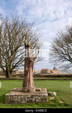 La statue de saint Aidan à Priory avec château de Lindisfarne dans la distance. L'Île Sainte, Northumberland, England, UK, Grande-Bretagne Banque D'Images
