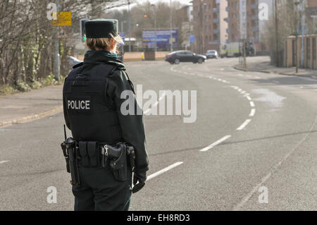 Une femme de la police monte la garde à une route à Belfast, tandis qu'Atos Origin de l'armée de désamorcer une bombe qui a été laissé dans un quartier résidentiel. Banque D'Images