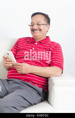 1 Indian Senior man sitting canapé composant Mobile Phone Banque D'Images