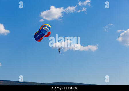 Le parachutiste parachute coloré dans un ciel bleu avec quelques nuages. Banque D'Images