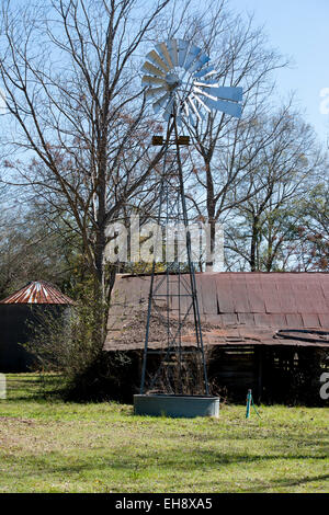 Moulin, grange et silo à grains dans un champ d'herbe verte entouré de chênes et un ciel bleu Banque D'Images