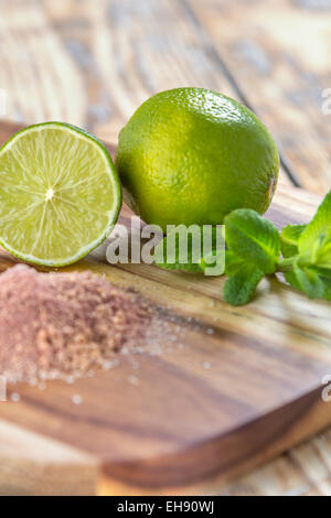 La menthe citron vert et le sucre brun les ingrédients d'un Mojito Cocktail sur une table en bois rustique Banque D'Images