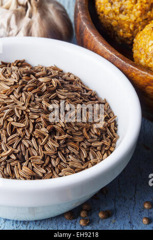 Les graines de cumin dans un bol blanc sur fond de bois Banque D'Images