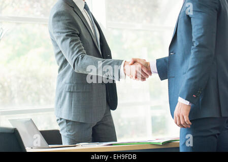 Businessmen shaking hands in office Banque D'Images