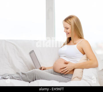 Smiling pregnant woman with tablet PC ordinateur Banque D'Images