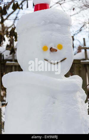 Bonhomme de cour avec des yeux jaune carotte closeup portrait d'hiver des enfants heureux souriant vertical fabriqué à partir de la neige Banque D'Images