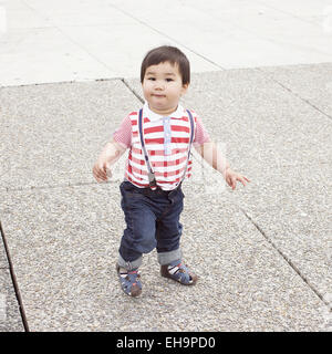 Baby Boy walking on sidewalk avec snack-dans la main Banque D'Images