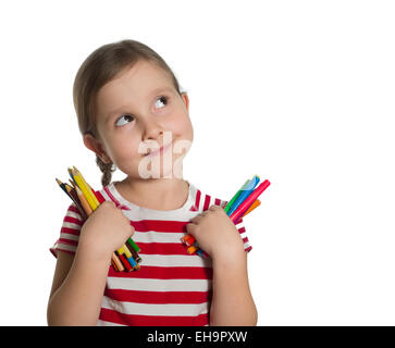 Cute little girl holding colorful crayons et marqueurs jusqu'à imaginer des idées isolé sur fond blanc Banque D'Images