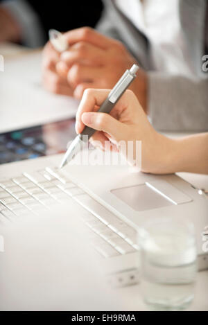 Businesspeople using laptop computer at meeting, cropped Banque D'Images