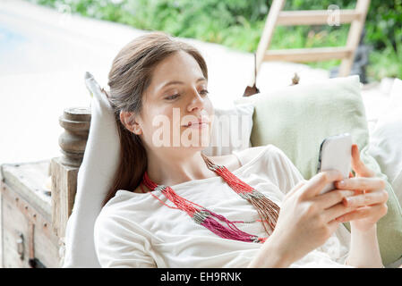 Jeune femme couchée sur le dos, en utilisant smartphone outdoors Banque D'Images