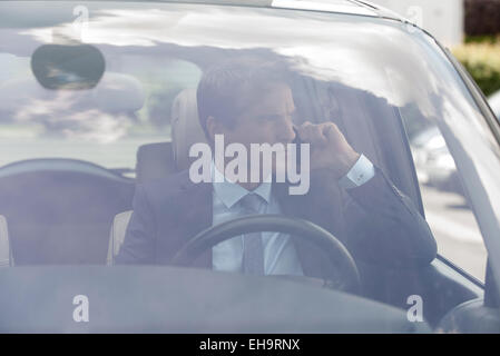Businessman talking on cell phone in car Banque D'Images