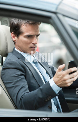 Man reading text message pendant la conduite Banque D'Images