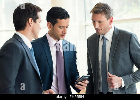 Couple avec des collègues, looking at smartphone Banque D'Images