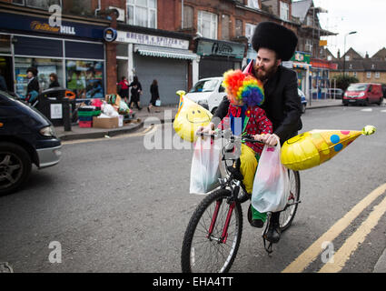 Jeudi 5 mars, 2015 Un homme marche juifs ultra-orthodoxes le long de cycles avec son enfant habillé en robe de soirée pour célébrer le peuple juif de Pourim à Stamford Hill quartier de Londres. Banque D'Images