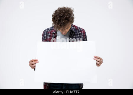 Young man holding blank billboard et à la recherche sur elle Banque D'Images