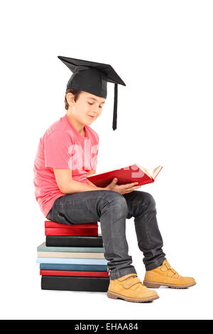 Kid avec mortier de lire un livre assis sur une pile de livres isolé sur fond blanc Banque D'Images