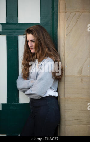 Un jeune 1314 moody 15 ans adolescente avec de longs cheveux bruns à l'extérieur seule par elle-même UK Banque D'Images