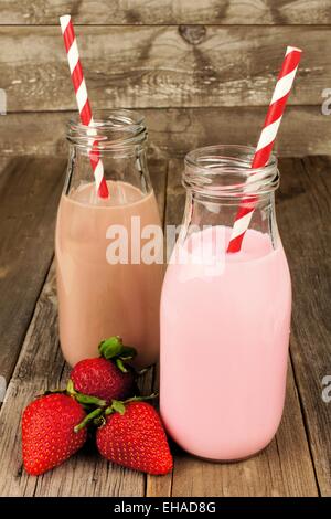 Fraise et Chocolat au lait en bouteilles traditionnelles avec paille sur fond sombre Banque D'Images