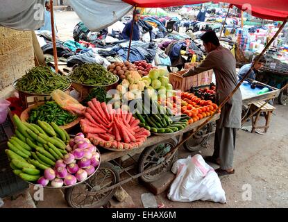 Vendeur de fruits et légumes tend à son panier hors marché Empress Karachi Pakistan Banque D'Images