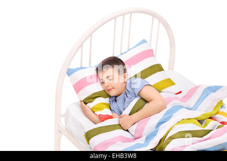 Adorable petit garçon endormi dans un lit confortable isolé sur fond blanc Banque D'Images