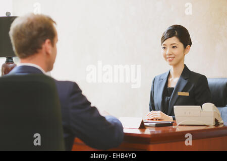 Japanese female concierge de l'hôtel traiter avec un client Banque D'Images