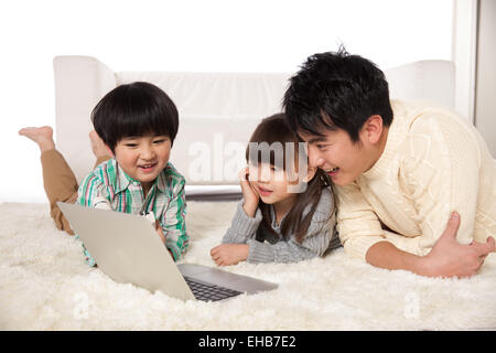 Pères et fils et filles d'utiliser les ordinateurs de poche sur le tapis Banque D'Images